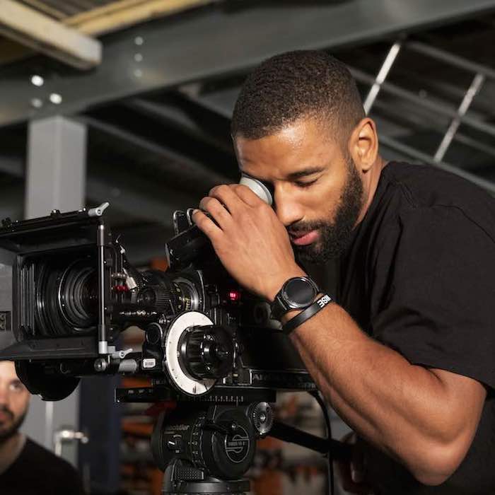 African American male film student looking through camera lense
