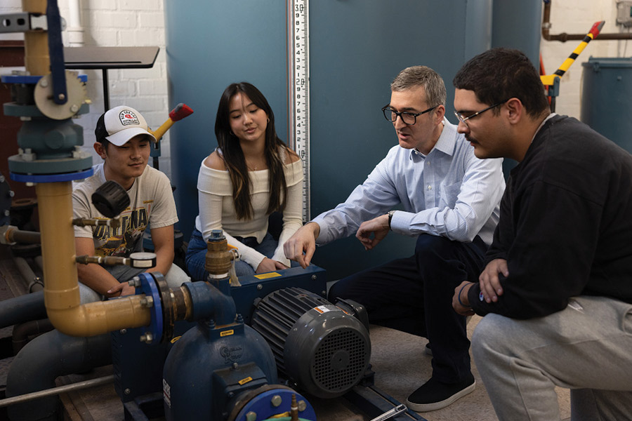 LMU Students and Professor gather around a piece of machinery