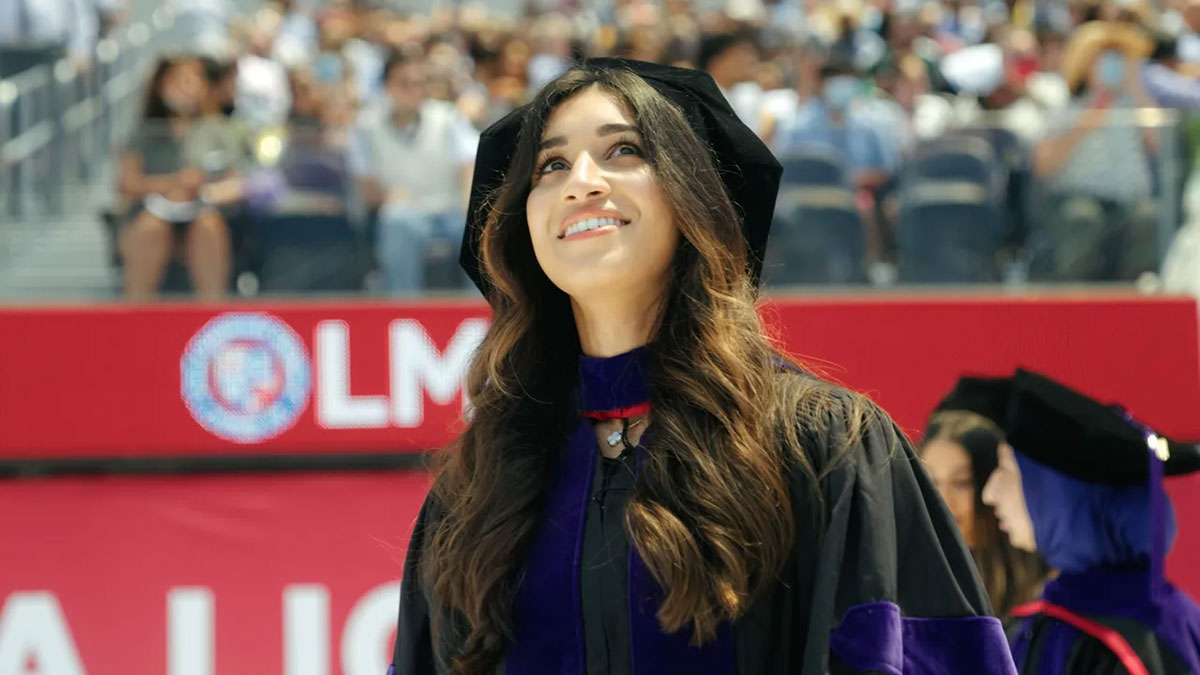 A graduate walking onto SoFi field and looking up at the stadium and crowd in awe