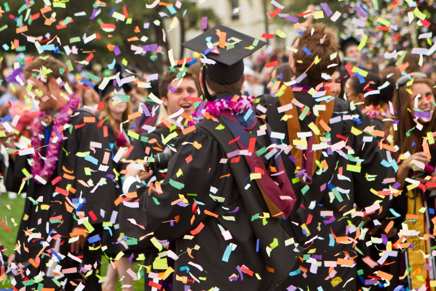 Students in cap and gown after graduation with confetti in the air