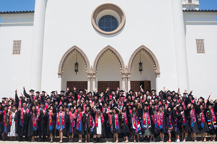 All of the LatinX graduates cheering in their cap and gowns outside of Sacred Heart Chapel