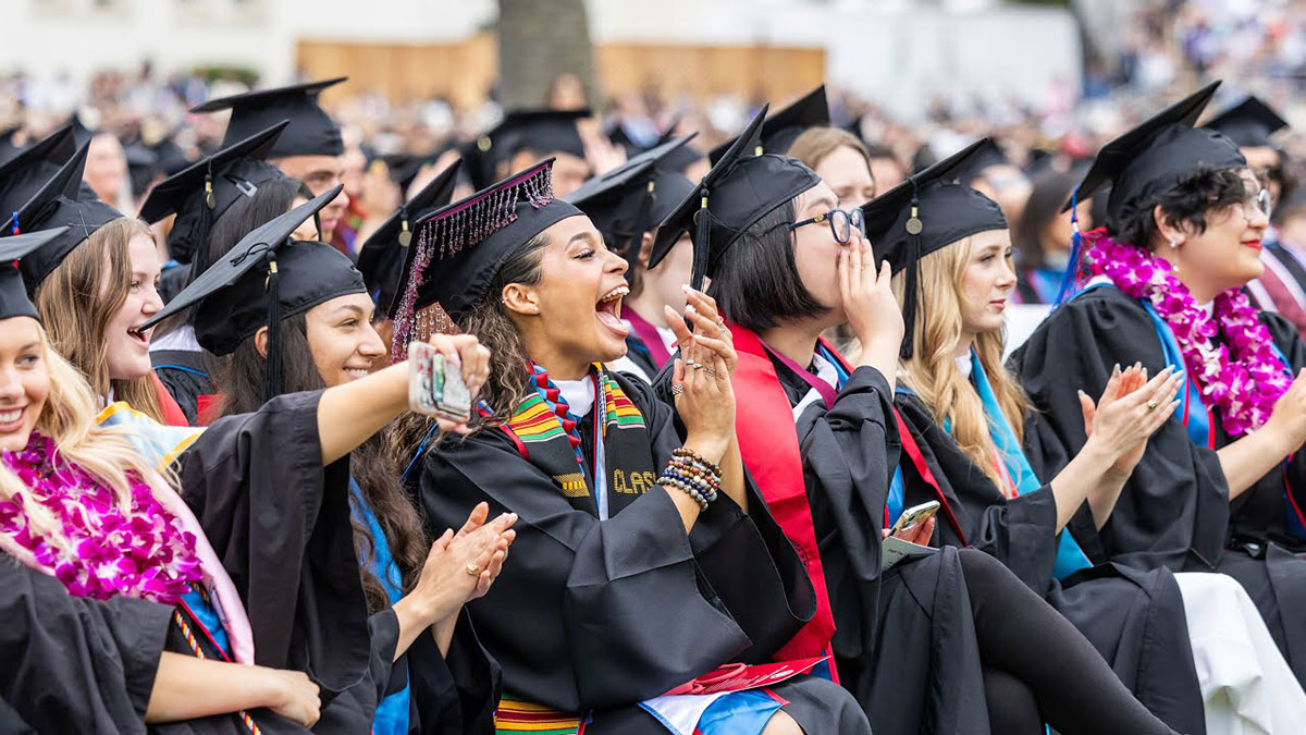 Graduates cheering from their seats during commencement