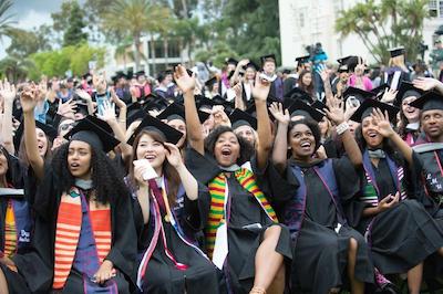 Students with raised hands in celebration at commencement