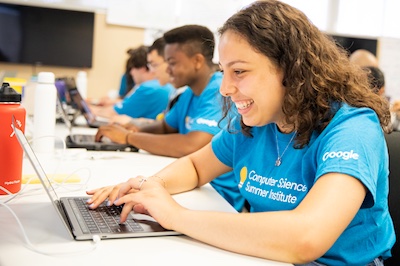 Female CSSI program student smiling while working on computer