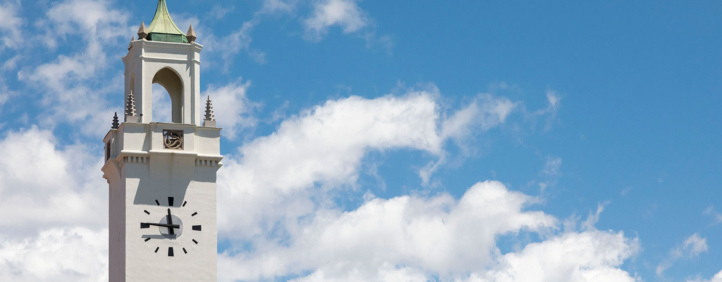 The Sacred Heart Clock Tower in front of blue sky and white fluffy clouds